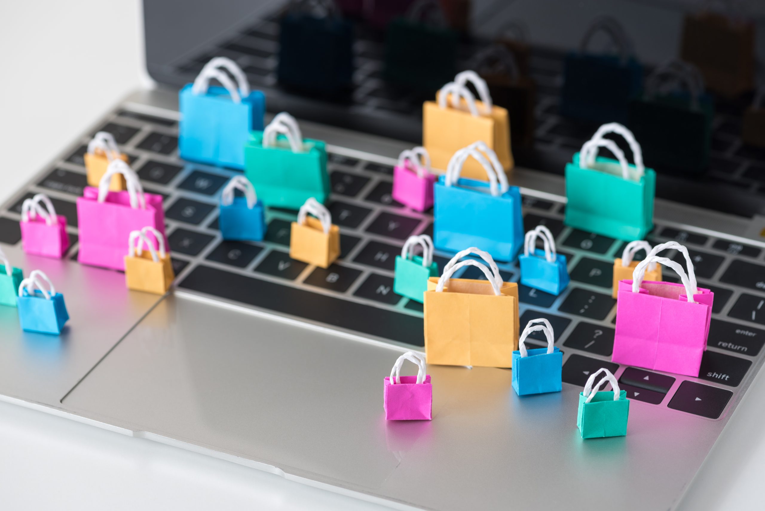 Colourful shopping bags beside a laptop